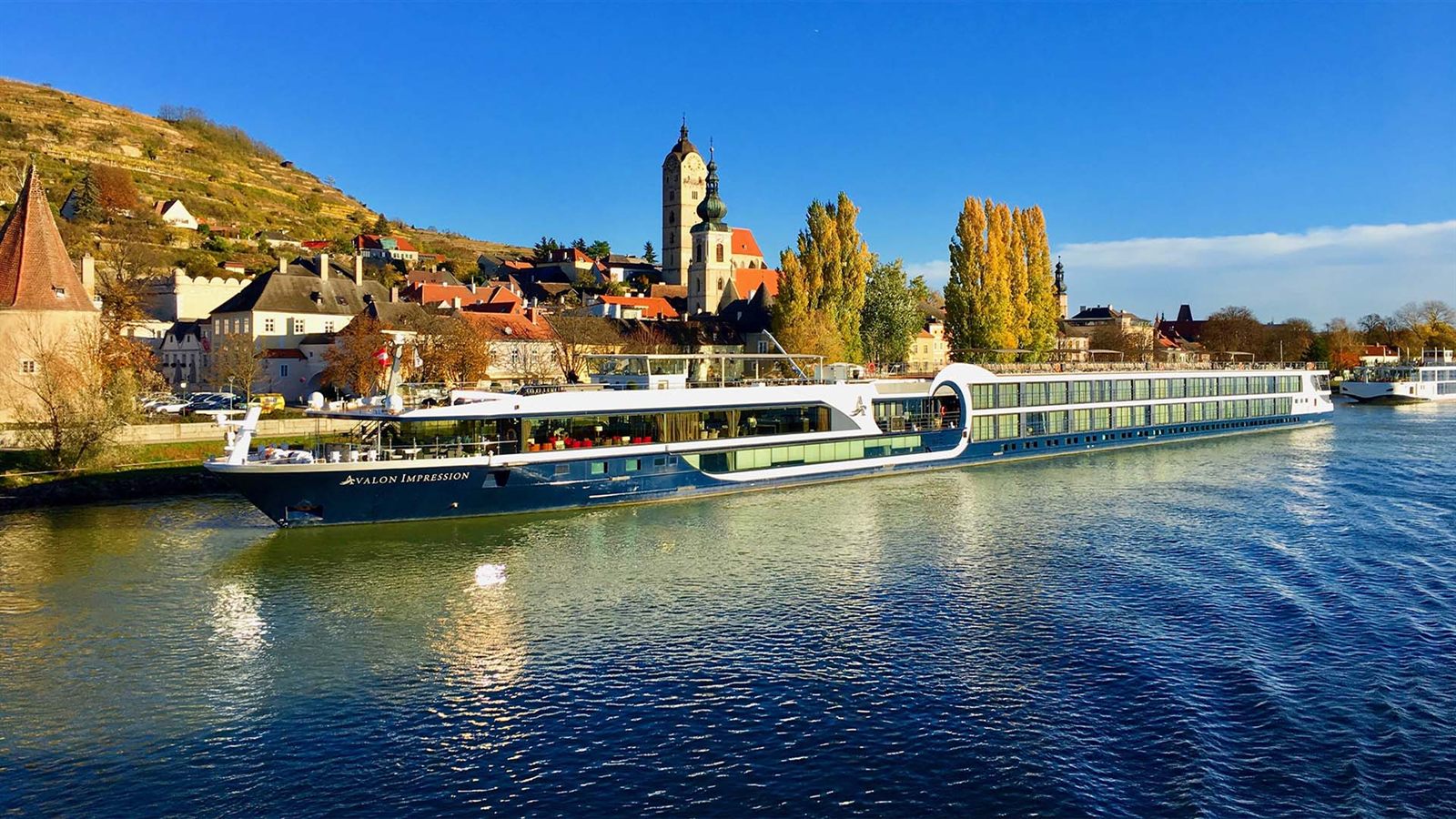 Long river cruise ship sailing past a vineyard village on the Danube
