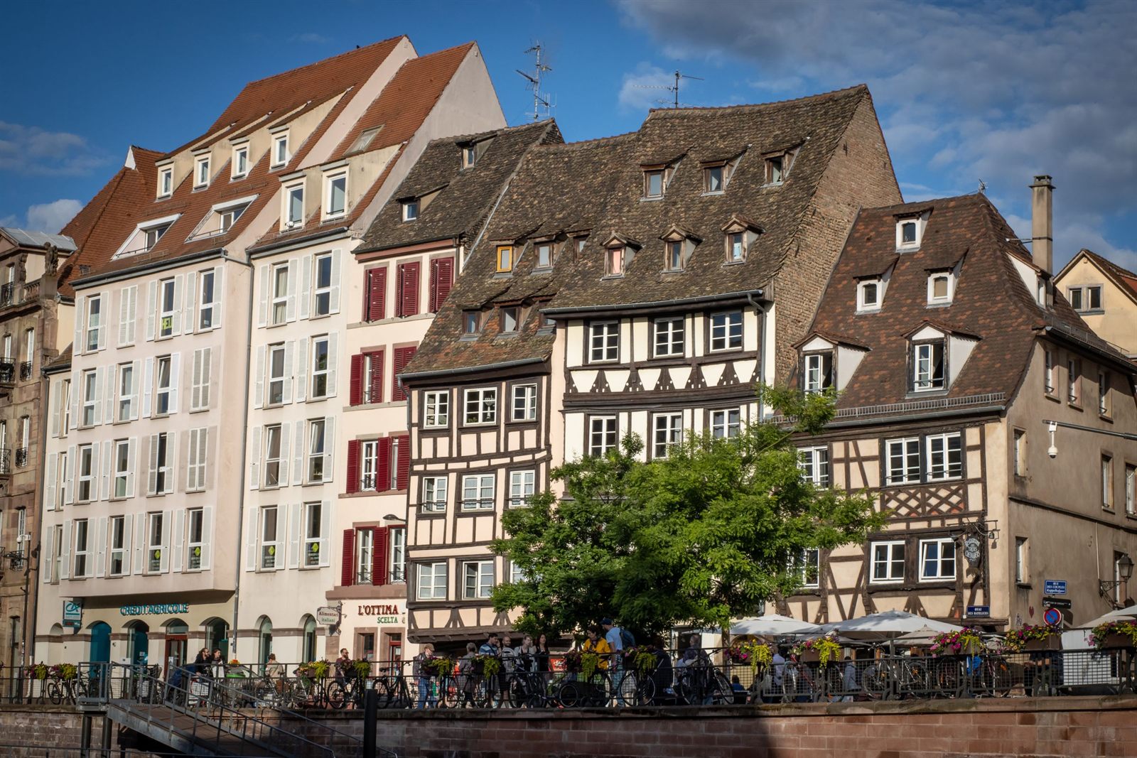 Half-timbered houses and cafe terraces along a river quay in Strasbourg